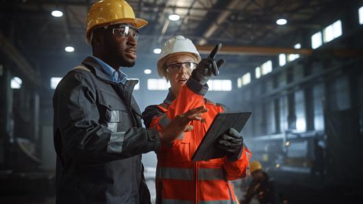 Two industrial workers in hard hats talking
