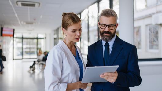 Two health care workers standing and looking at a chart together