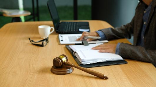 Lawyer sitting at desk with laptop, legal pad and gavel.