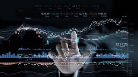 Hand on screen with graphs. 