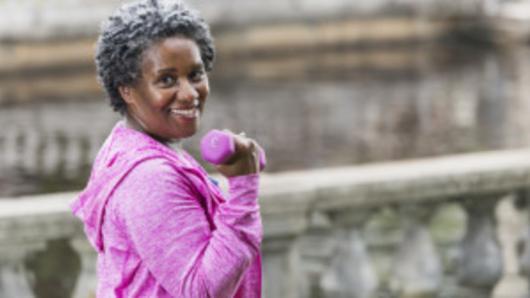 Woman holding a hand weight and smiling. 