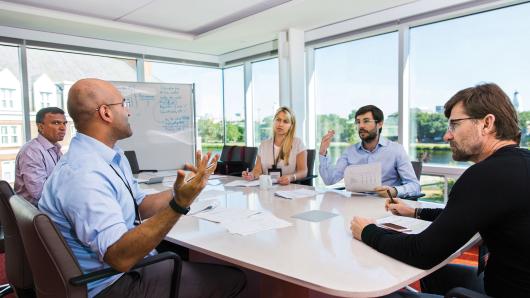 Diverse group of executives in discussion around a table.